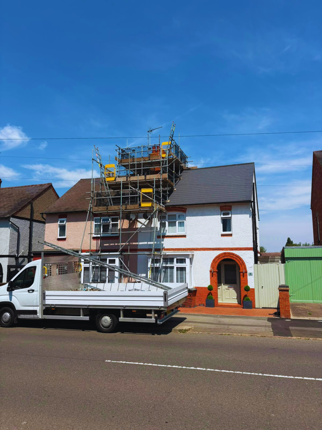 Chimney scaffold platform above a render and brick house with our truck on the road