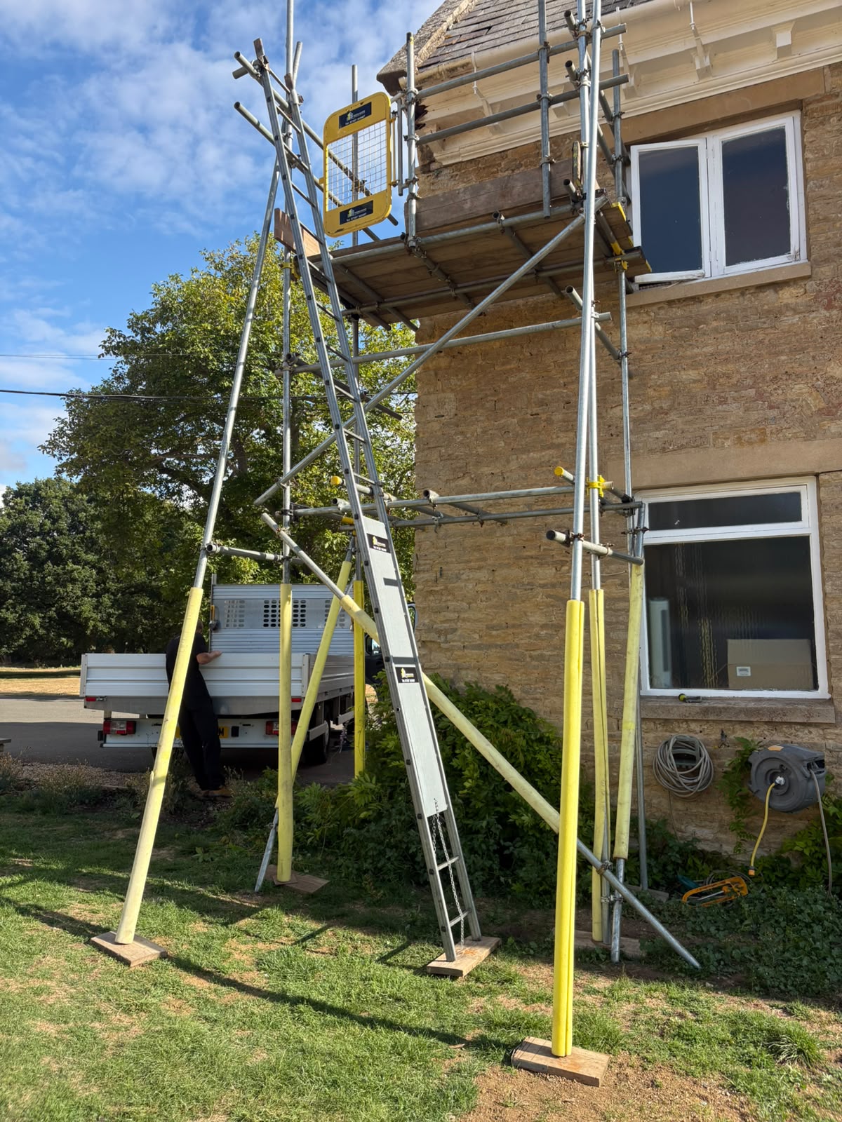 Tower scaffold with raking supports giving access to the eaves of a stone cottage