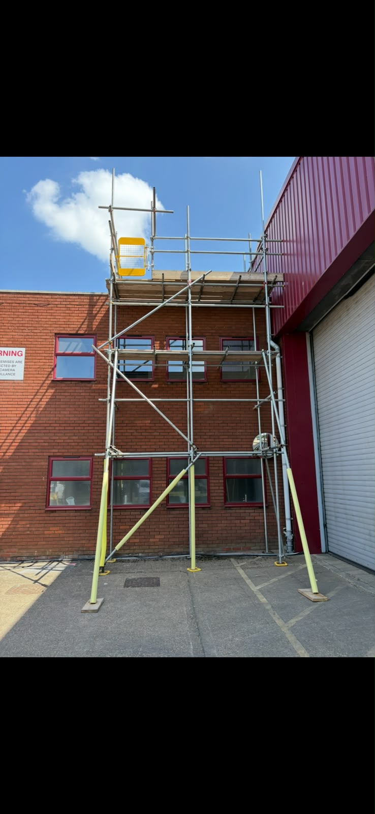 Tower scaffold providing access to a red brick commercial unit elevation