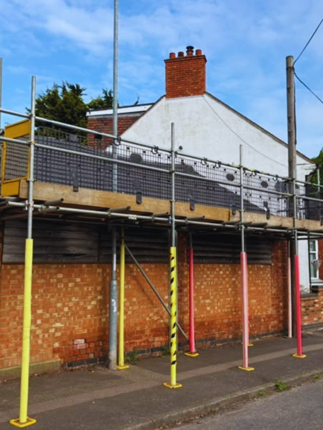 Pavement scaffolding with padded uprights standing on the footway