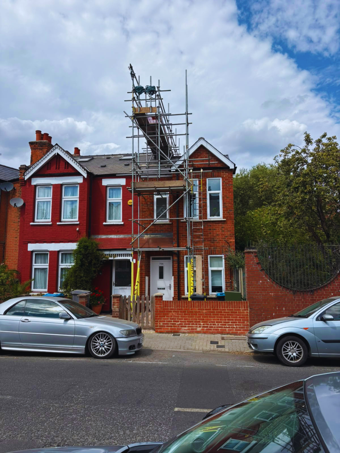 Chimney scaffolding to the roof of a red brick semi-detached house